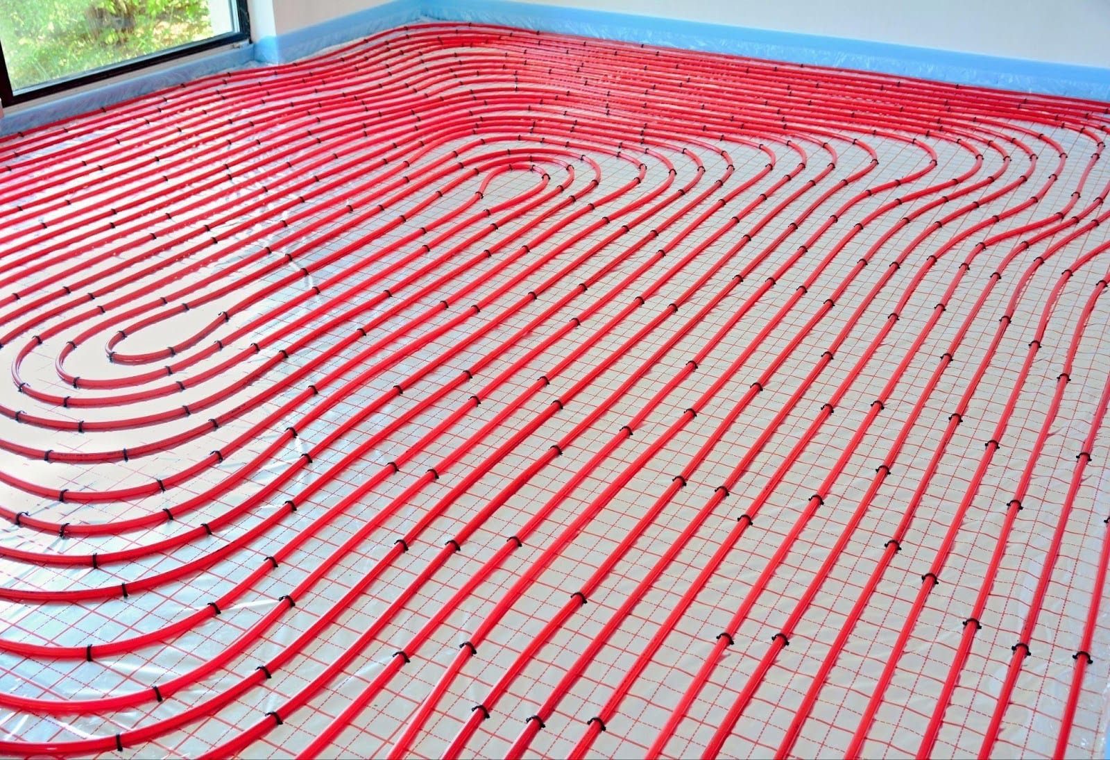 Interior view of a room with exposed red heating pipes and a simple floor showcasing a utilitarian aesthetic