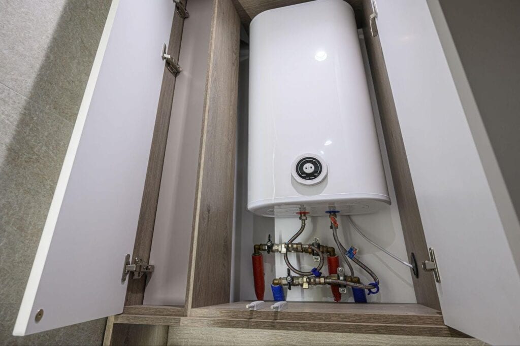 A water heater installed in a cabinet featuring visible pipes and valves for plumbing connections