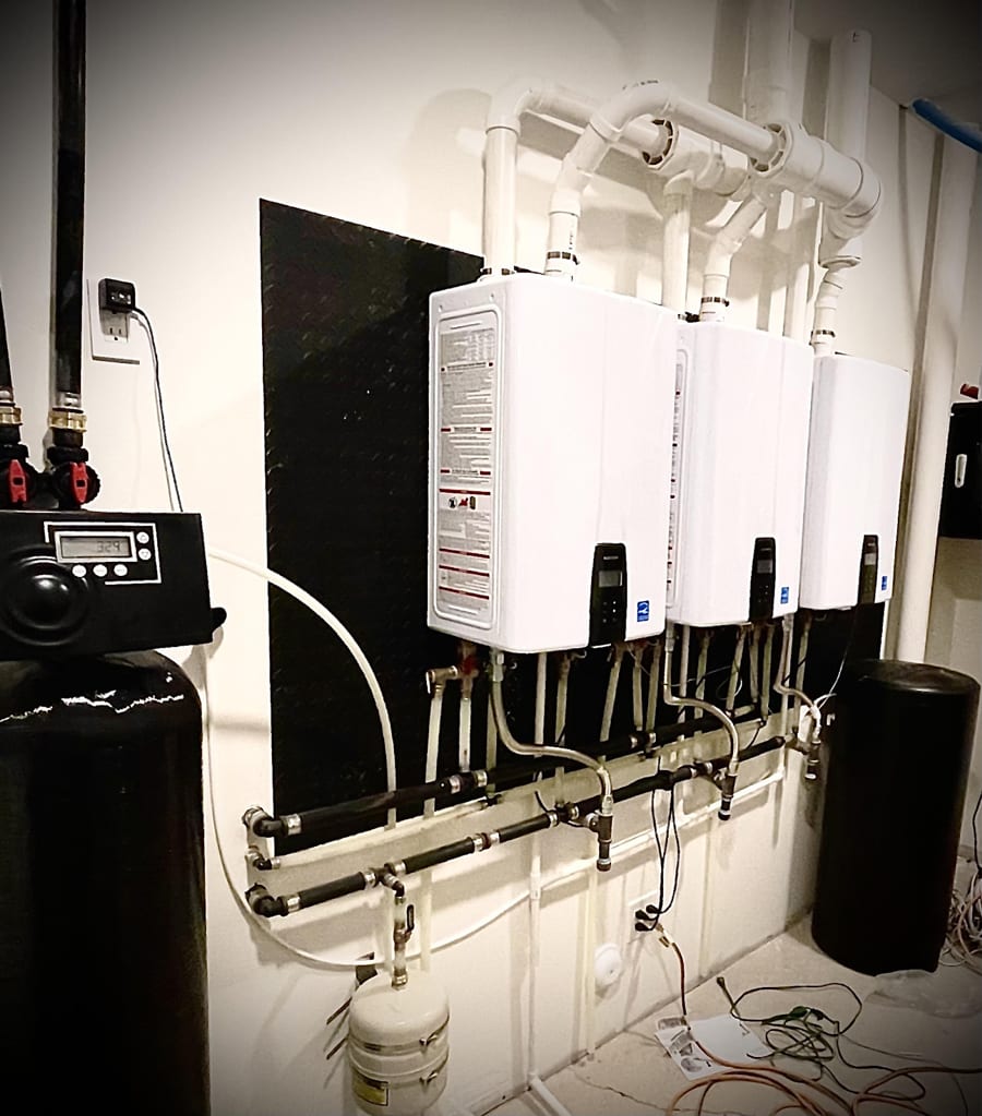 Room filled with water heaters and pipes for plumbing.