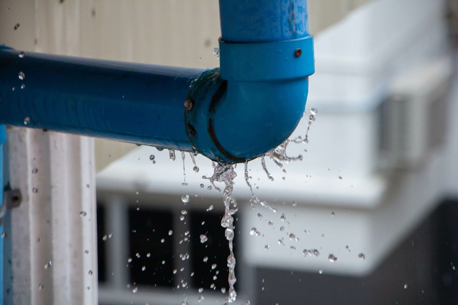 Burst blue pipe with water leakage causing damage.