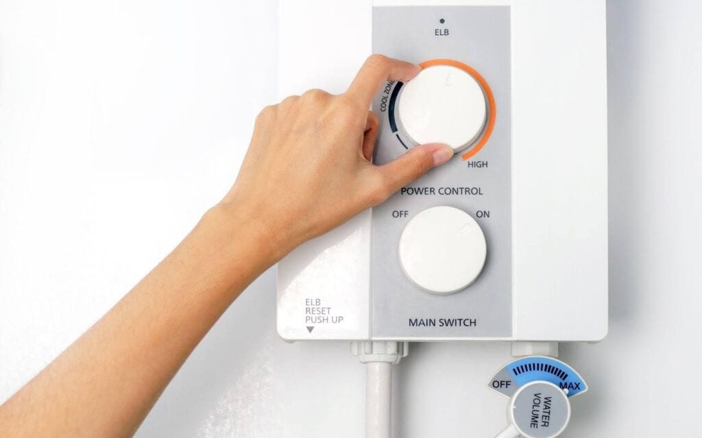 A hand pressing the button on a water heater indicating a temperature adjustment for heating water