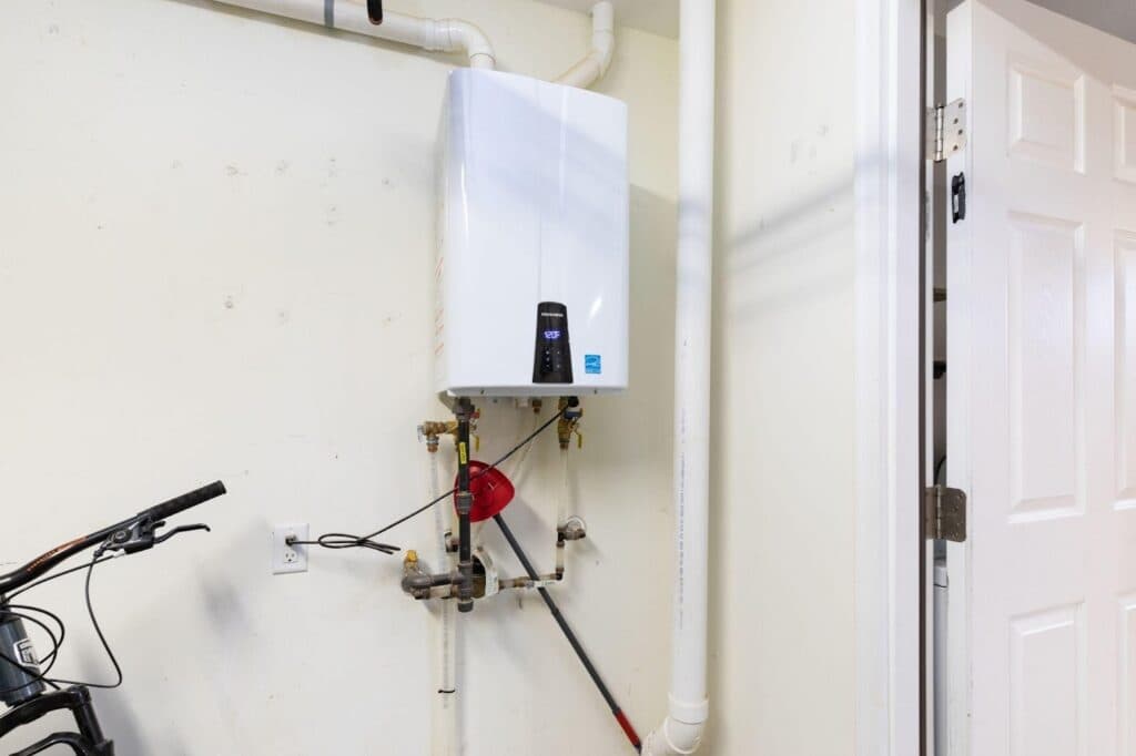 A water heater is installed on the wall next to a parked bike illustrating a compact utility space