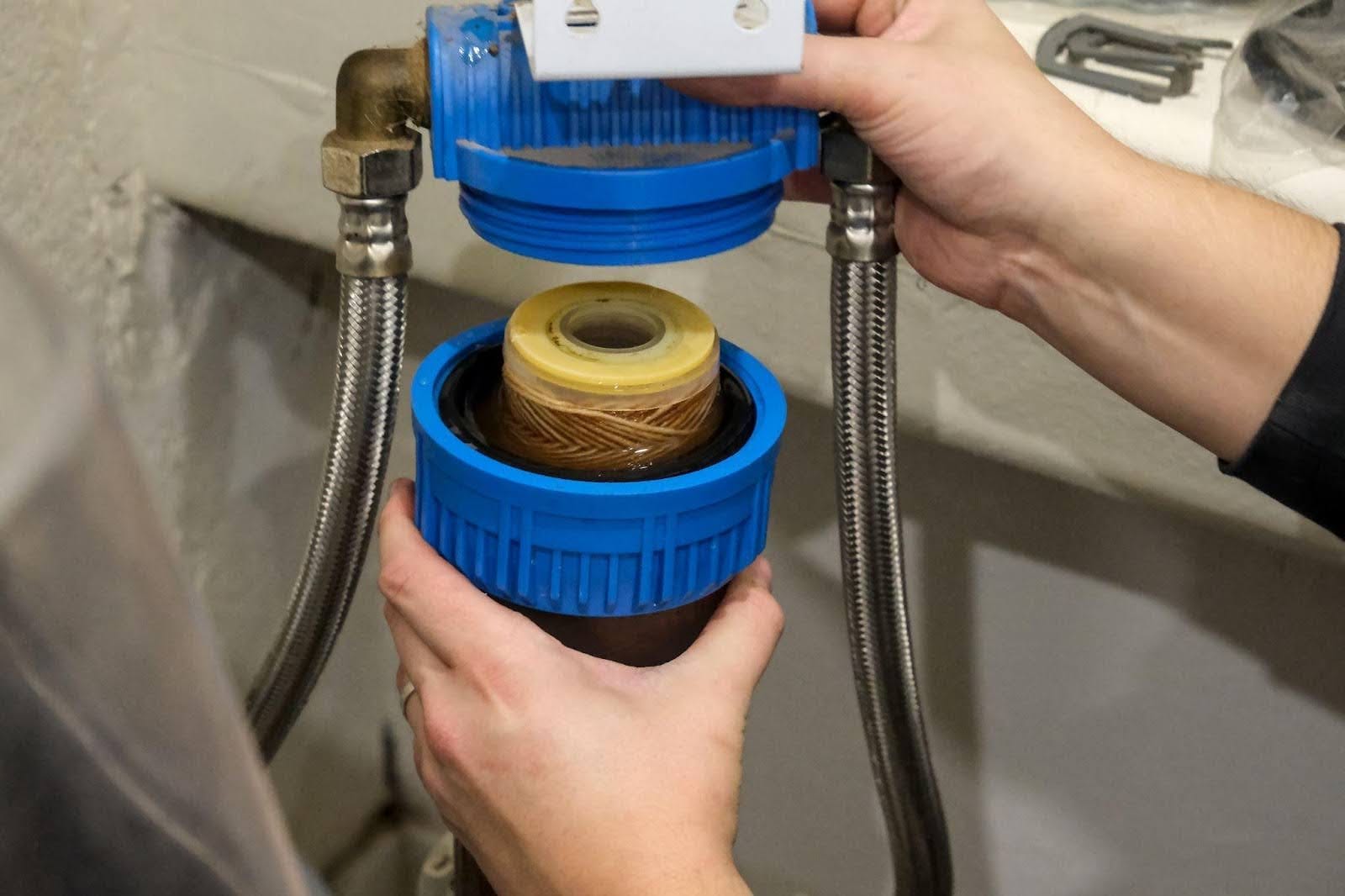 A person fills a water tank using a blue hose demonstrating a practical water management task