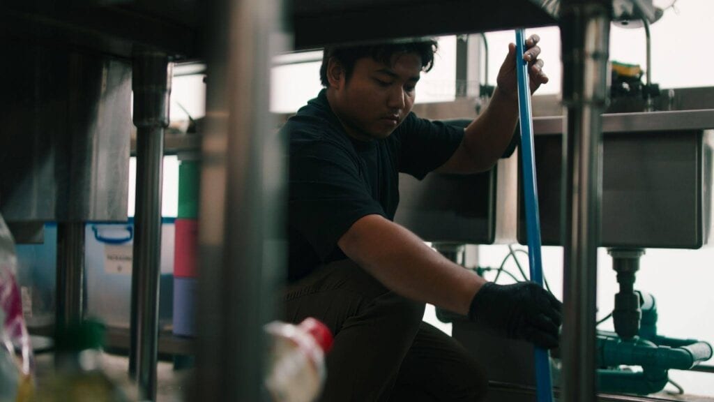 A man in a black shirt is cleaning the kitchen wiping down surfaces and organizing utensils