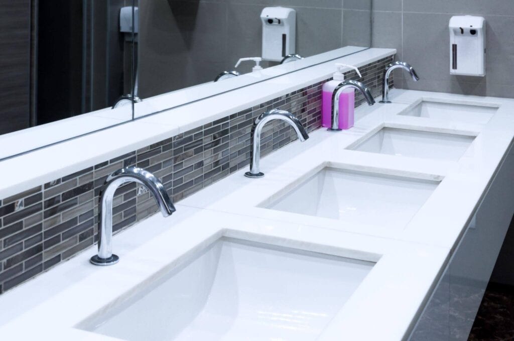 A spacious bathroom featuring four sinks and a large mirror above them