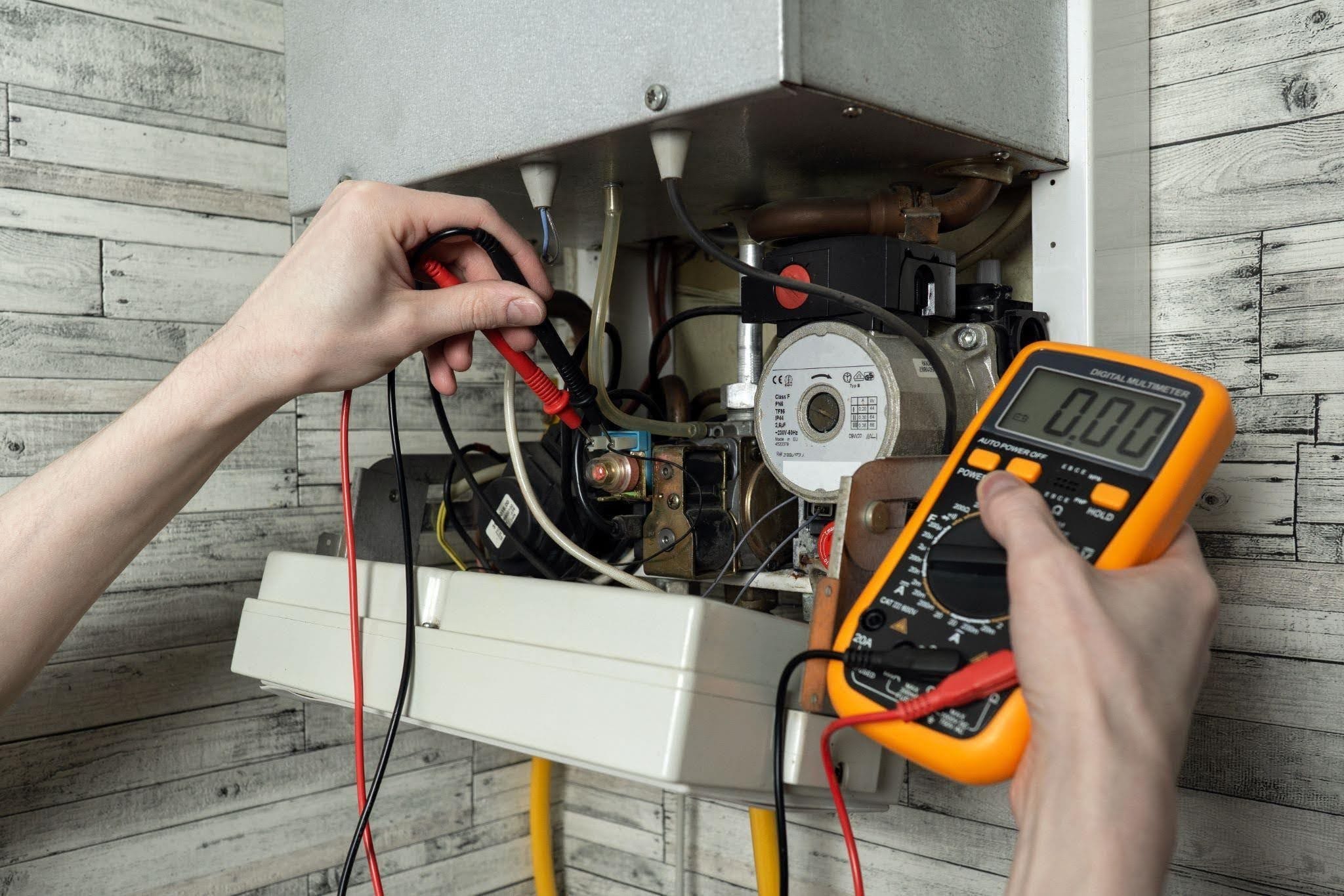 A technician measures the water heater temperature with a multimeter verifying its operational status and safety