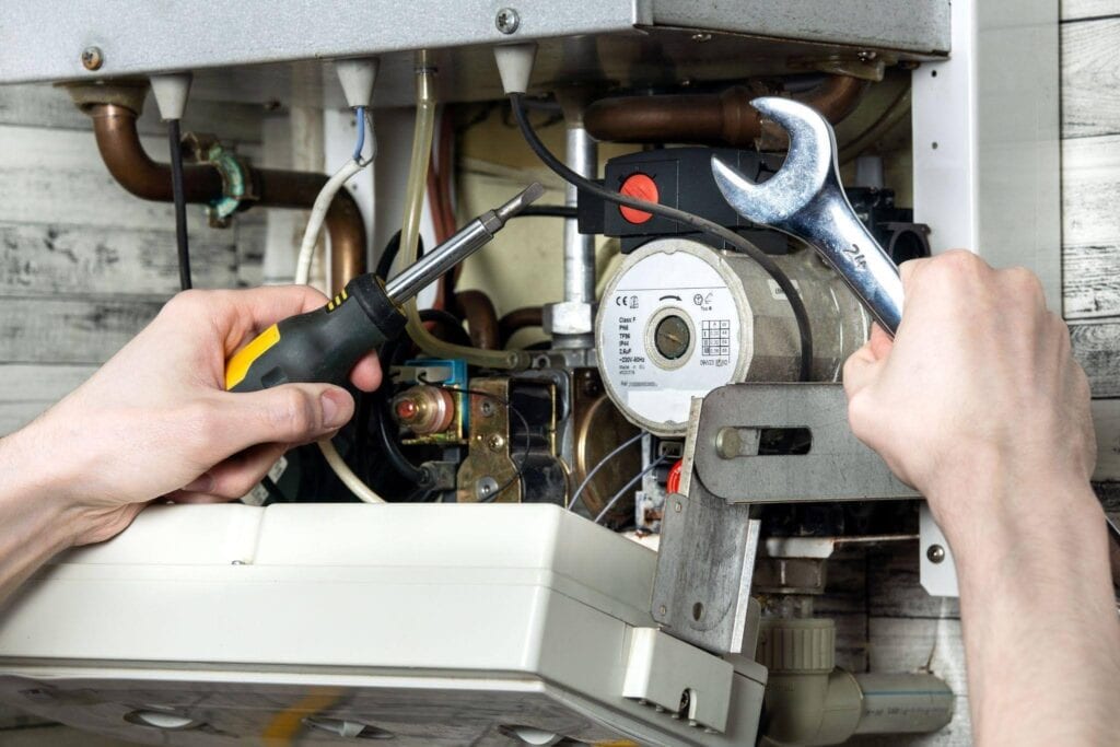 A technician working on a gas boiler employing a wrench to make necessary repairs