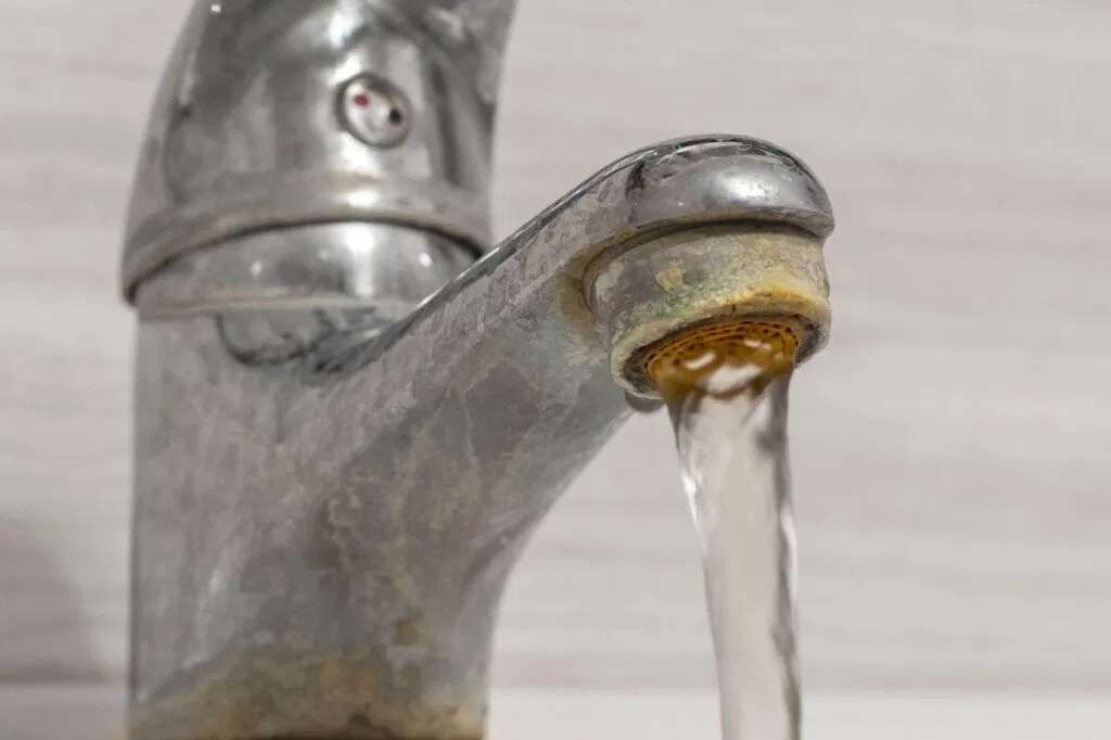 Close-up of a faucet with water flowing highlighting the stream and the shiny metal surface