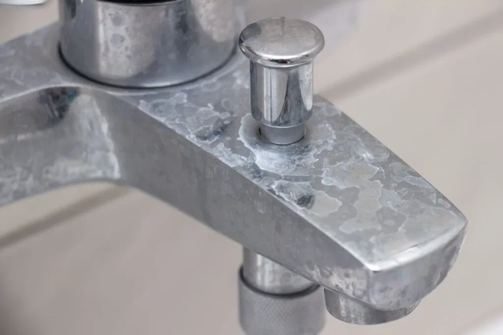 The white, flaky, crusty buildup on your chrome bathroom faucet is limescale (also called hard water deposits or calcium buildup).