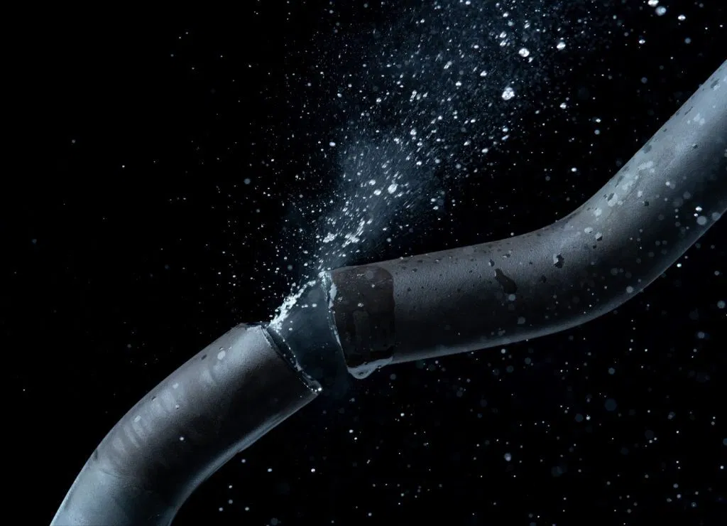 A burst water pipe with water gushing out, part of a plumbing system