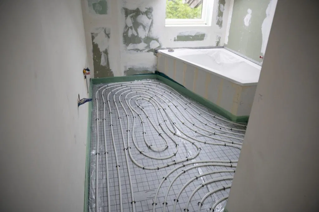 Bathroom with tub and shower, featuring radiant heating and traditional forced air heating systems