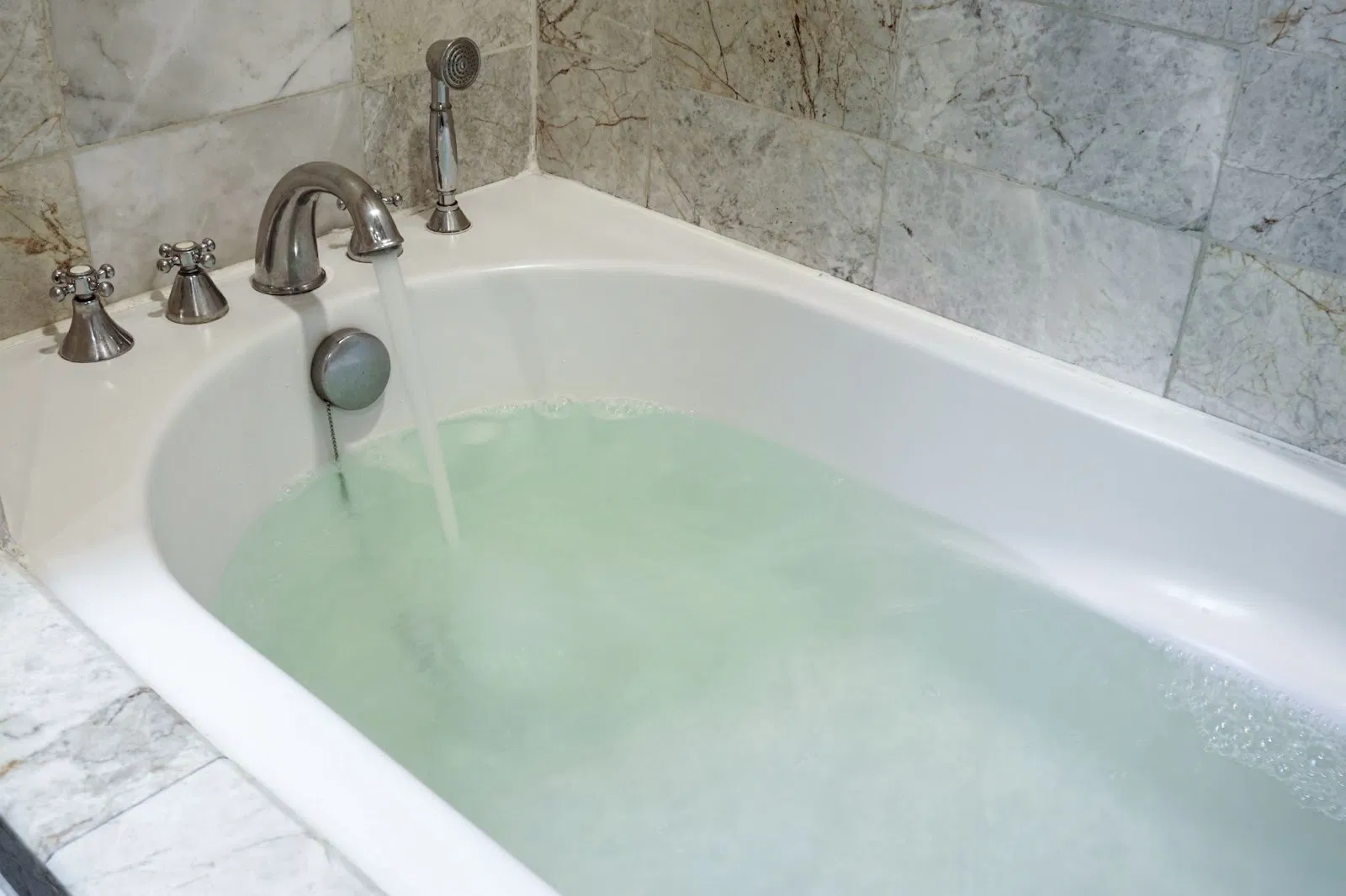 Bathtub filled with green water, symbolizing a plumbing project. Choose the right professional plumber for the job.