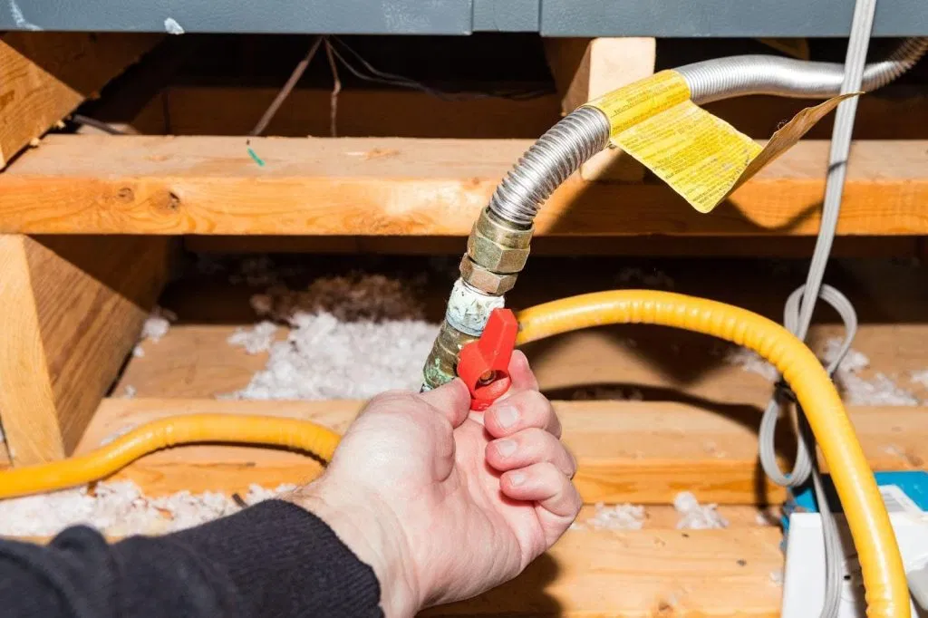 A technician repairs a furnace using a hose in a home environment