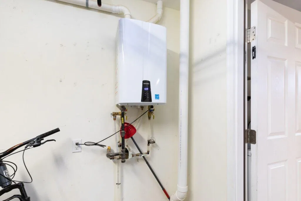 A water heater is installed on the wall next to a parked bike illustrating a compact utility space