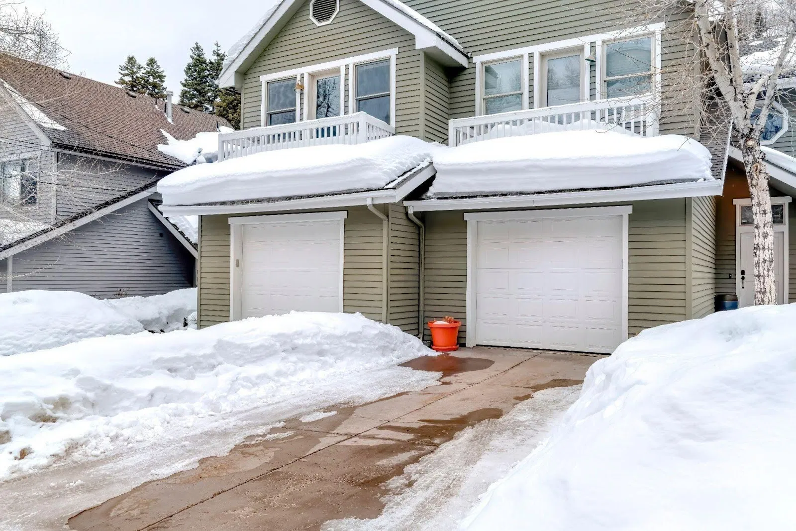A snow-covered house with a garage set against a wintry backdrop