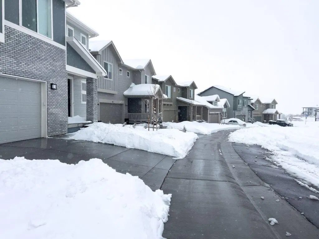 A snowy driveway stretches in front of a row of houses creating a serene winter scene