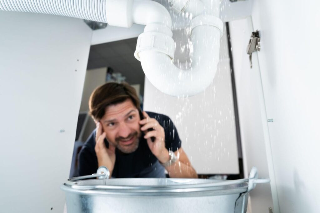 A man talks on his cell phone while positioned in front of a sink showing concentration during the call